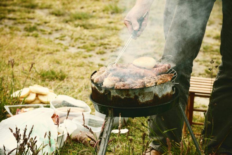 light weight camping grill cookign chicken, sausage, and vegetables