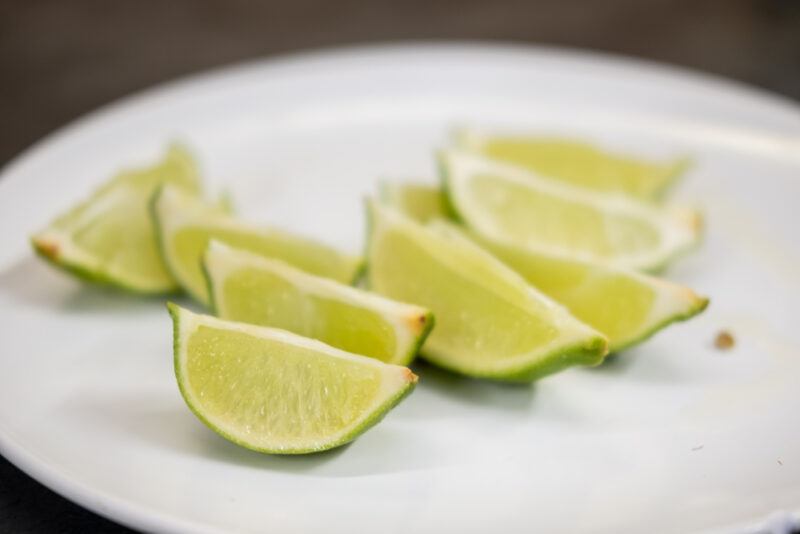 a closeup image of a white round dish with lime wedges