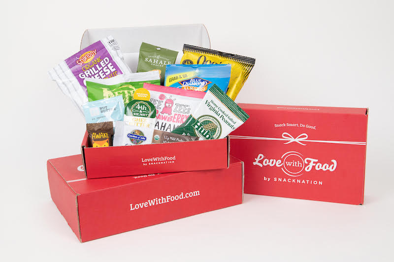 red box labeled 'love with food by snacknation' and a variety of packaged snacks sticking out of an open box.