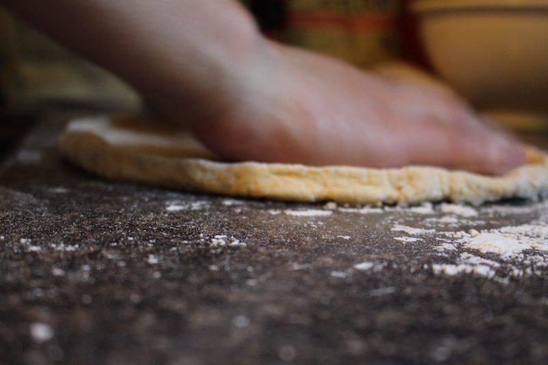 flattening the pizza dough on the counter with flour