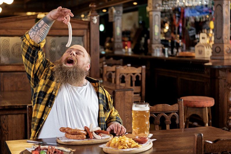 man in pub eating sausage with chips, beer, sausage, and other manly foods you can get in a subscription box