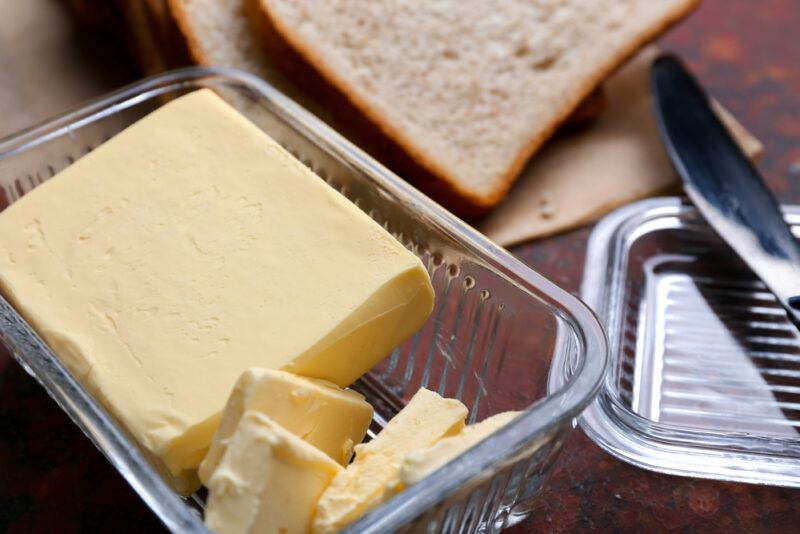 a tub of margarine with bread slices at the back and a butter knife beside it