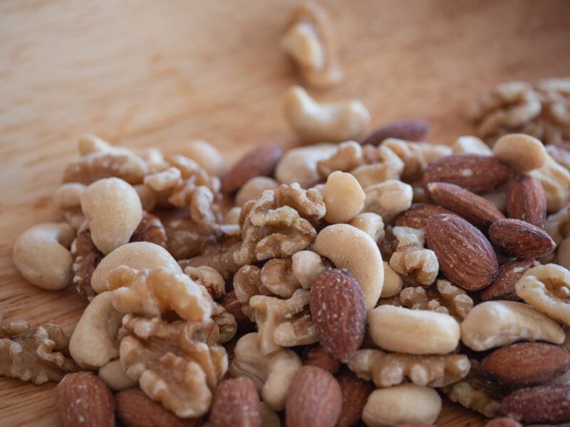 closeup image of a mound of mixed unsalted nuts on a wooden surface