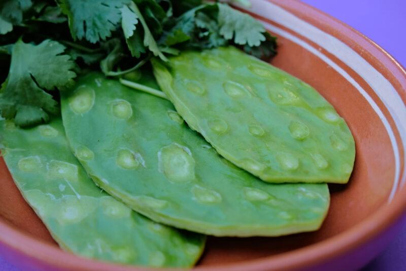 closeup image of a brown ceramic round dish with nopales and cilantro