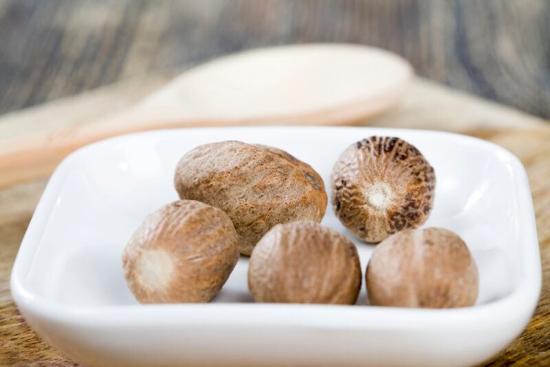 closeup image of a small square white dish with nutmegs on it