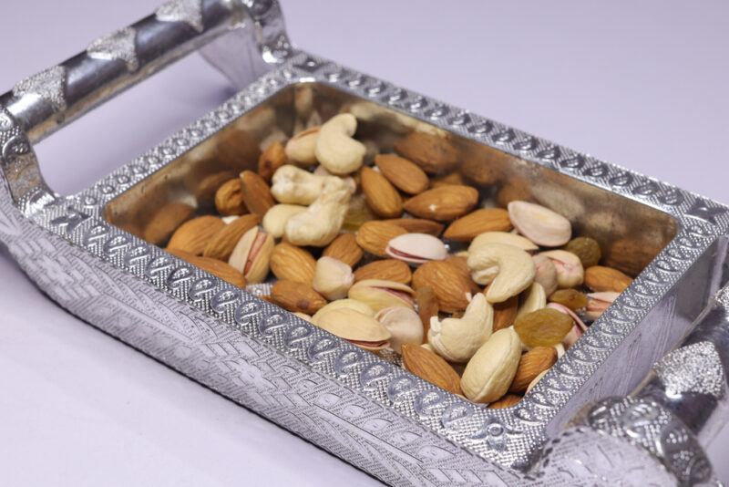 rectangular metal tray with two handles full of different types of nuts