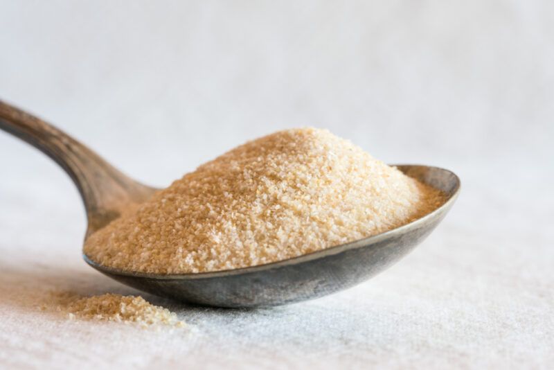 on a white surface is a closeup image of a silver spoon full of onion powder