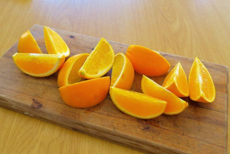 on a wooden chopping board is a wooden chopping board with orange wedges or slices