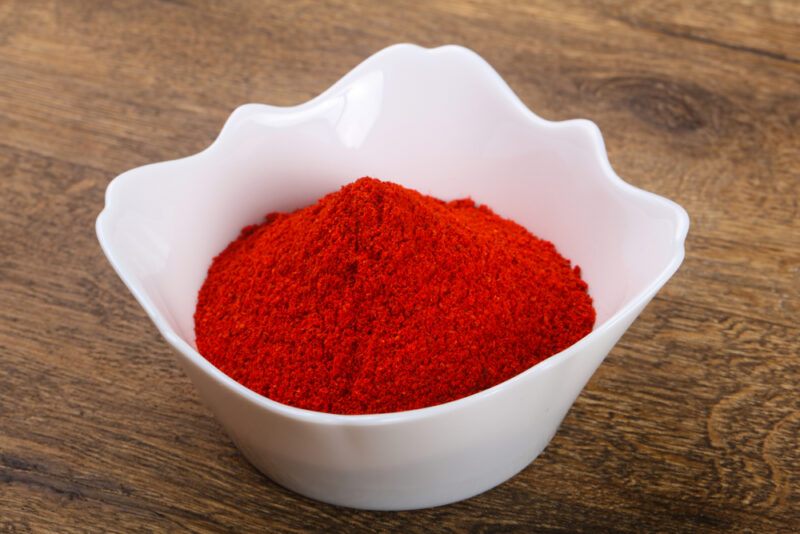 on a wooden surface is a white bowl with paprika powder