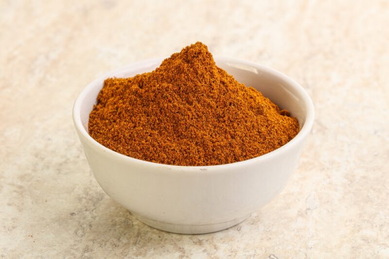 on a marble surface is a white bowl full of paprika powder