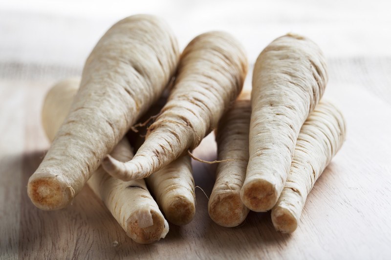 closeup image of a pile of parsnips on a wooden surface