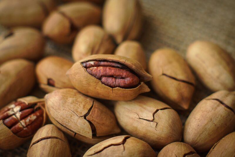 closeup image of a pile of pecans, with a few partially cracked