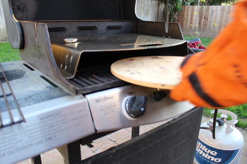 placing pizza stone under kettlepizza to preheat before cooking