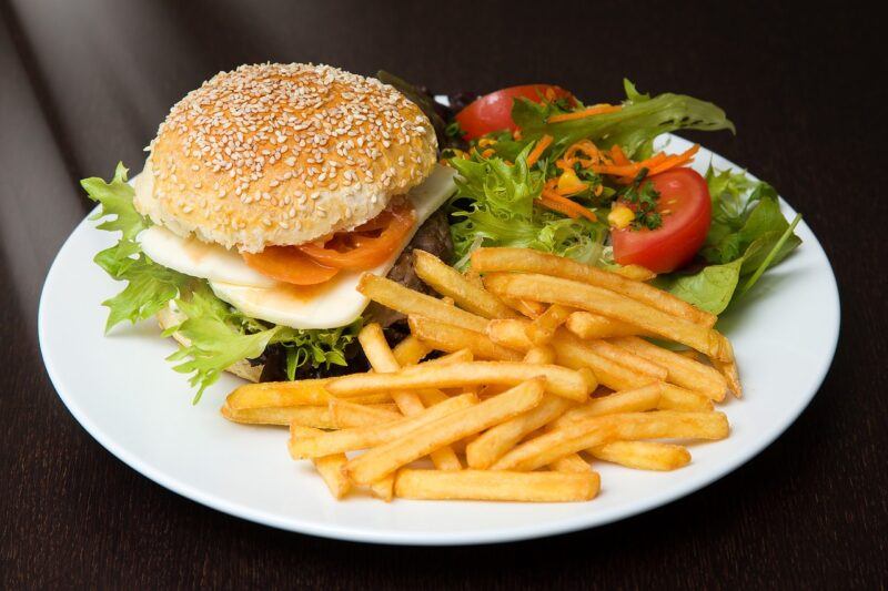 a plate with a burger, fries, and salad on a black tablecloth to represent the best plant based burger