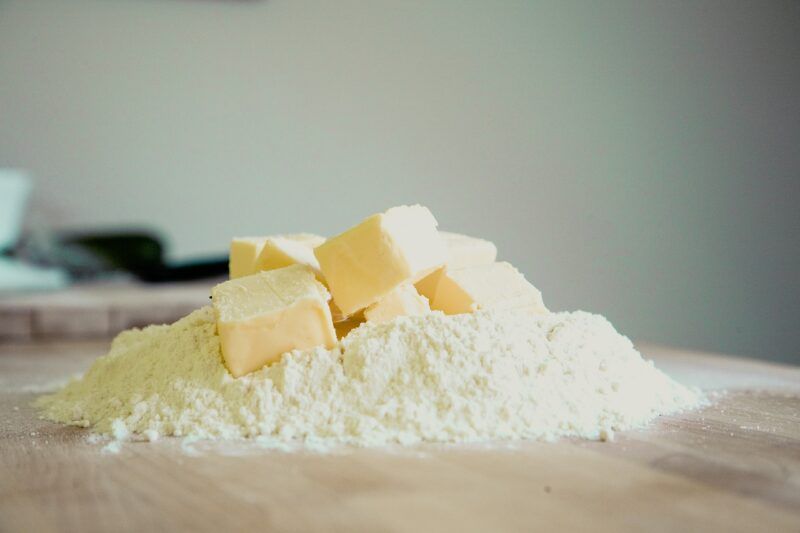 several squares of butter on a small pile flour sitting on a cutting board to represent plant-based butter