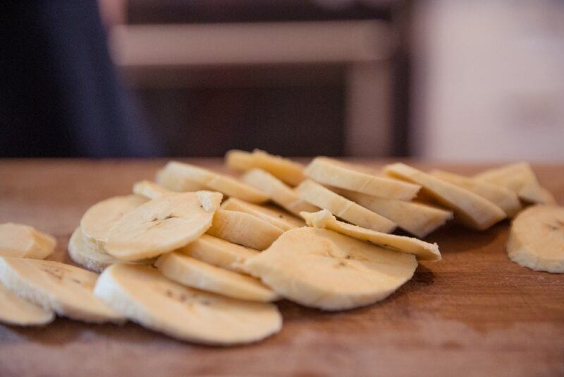 closeup image of a spread of sliced plantains on a wooden surfae