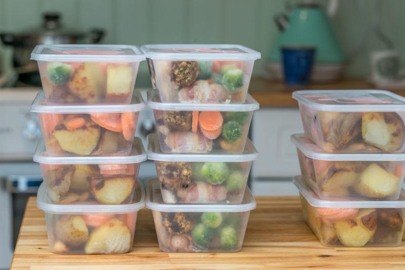 plastic containers with frozen fruits, meats, and vegetables with same ingredients for meal prepping