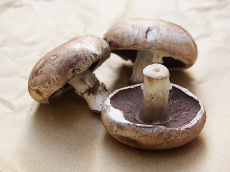 on a beige colored surface are three Portobello mushrooms