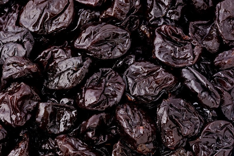 This photo shows a closeup view of several dark prunes.