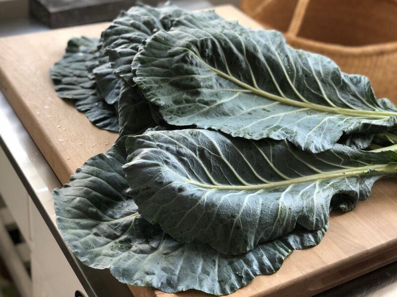 closeup image of raw collard greens on a wooden chopping board