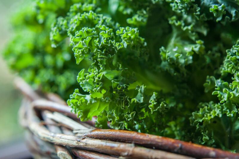 closeup image of raw kale in a woven basket