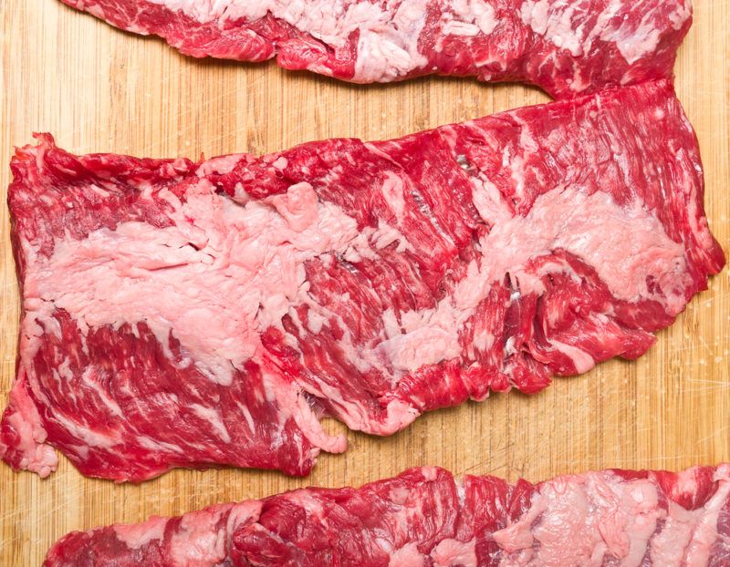 raw skirt steak on wooden cutting board