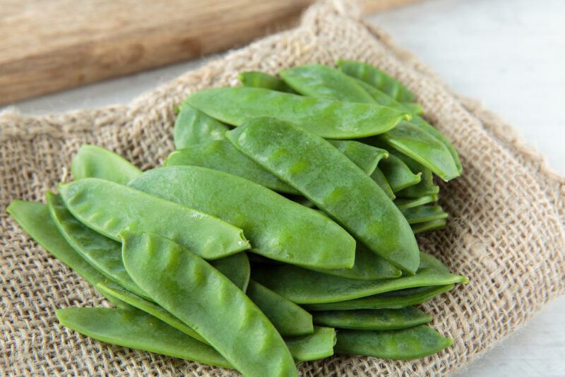 on a sack cloth are trimmed raw snow peas