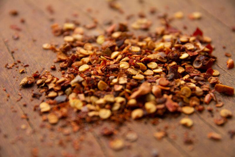 on a wooden surface is a small mound of red pepper flakes