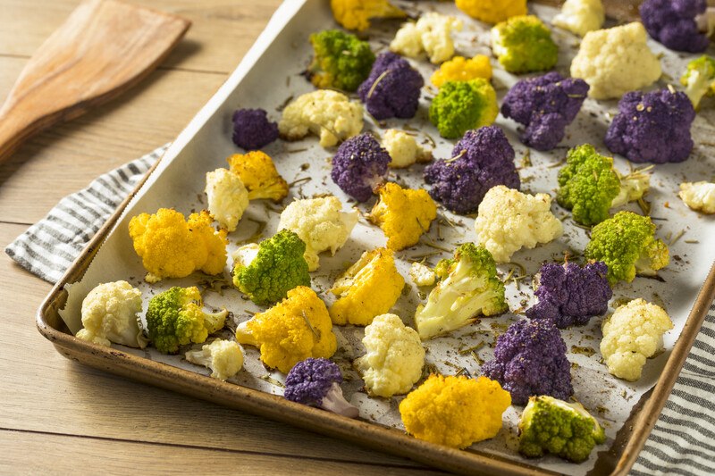 baking pan lined with baking paper with roasted different colored cauliflower florets