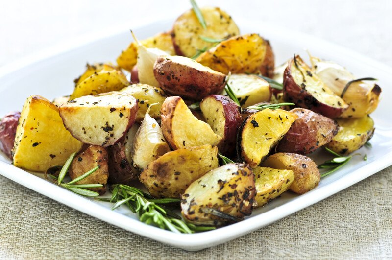 closeup image of a square ceramic dish with roasted potatoes with herbs