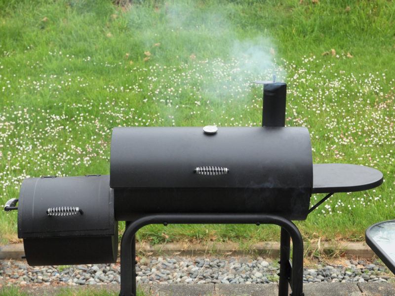 side box charcoal smoker with green grass background