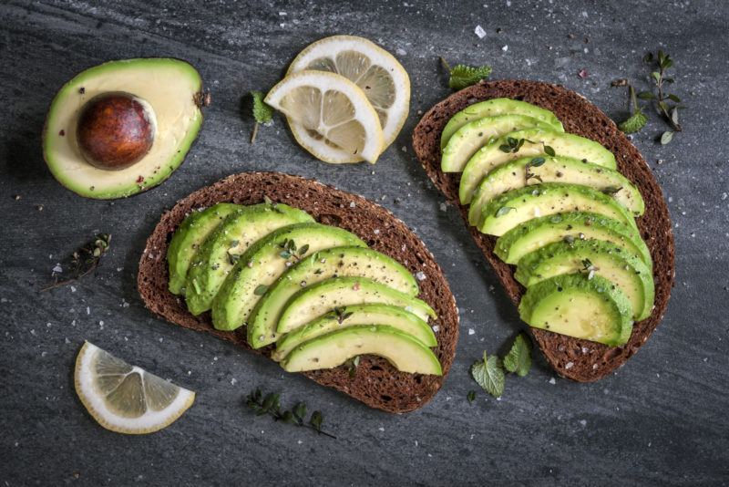 sliced avocado arranged neatly on two pieces of toasted rye bread. 