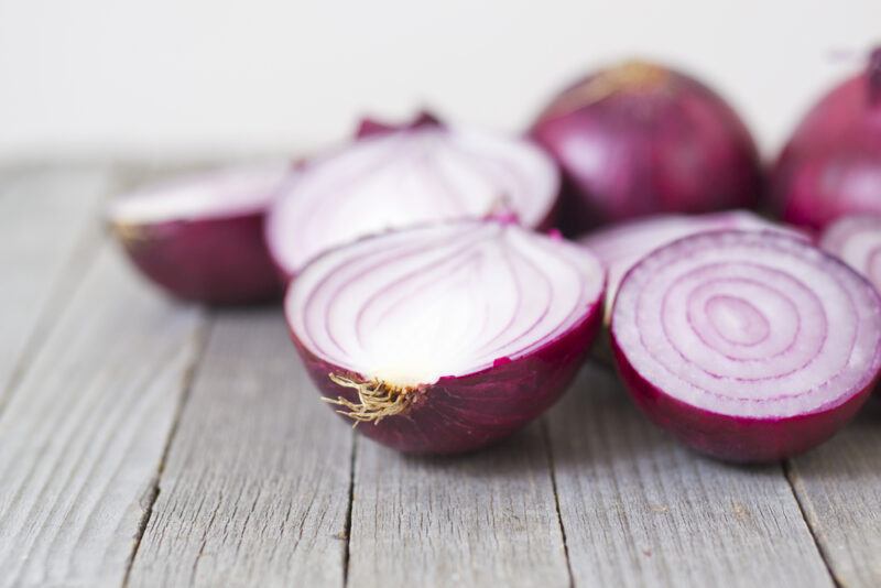 a closeup image of  cut onions on a rustic looking wooden surface