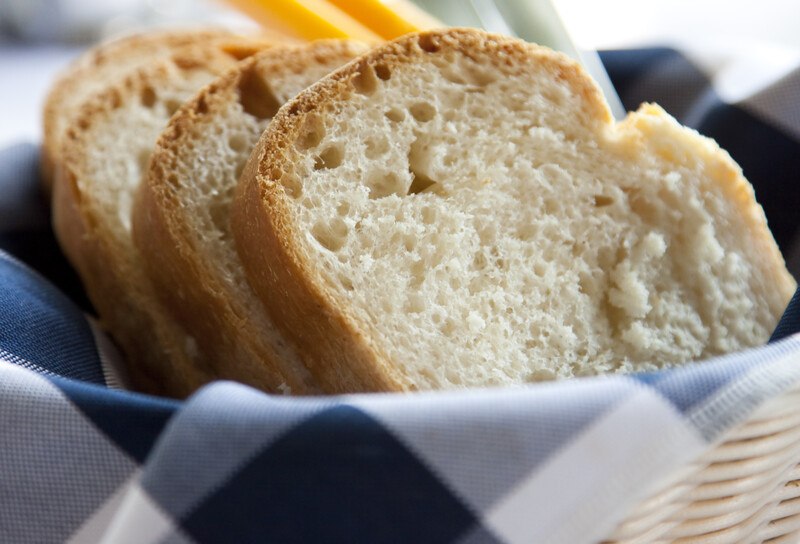 closeup image of slices of white bread in a basket lined with white and blue table napkin