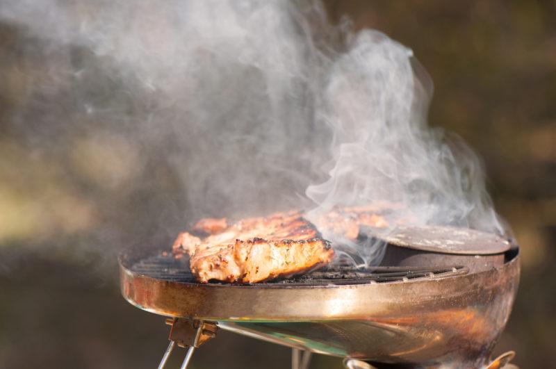 small ultralite grill with smoke coming off cooking pork chops