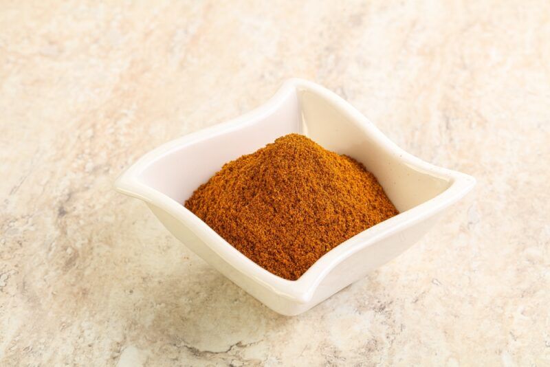 on a marble surface is a white square dish full of smoked paprika