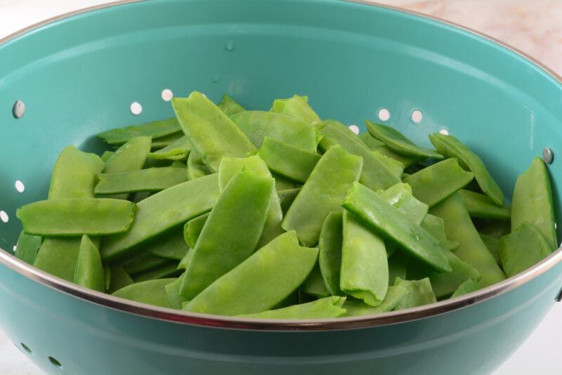 closeup image of a green bowl with snow peas