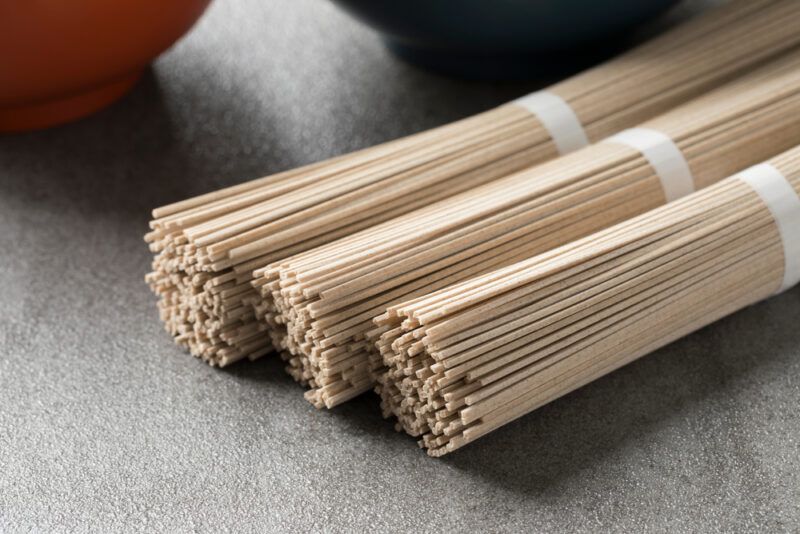 on a concrete surface is three bundle of raw soba noodles