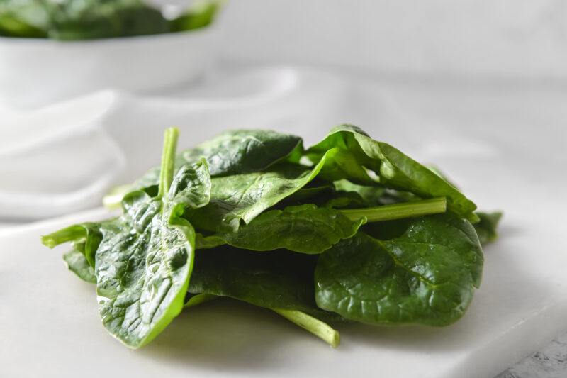 a closeup image of a pile of spinach resting on top of a white paper stone board