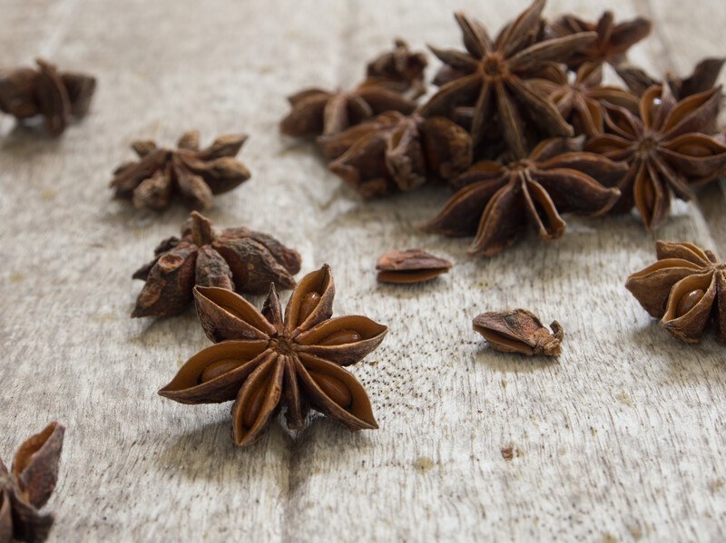 closeup image of some star anise spilled over an aged wooden surface