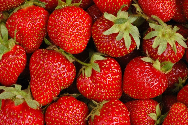 This photo is a closeup shot of several ripe, red strawberries.