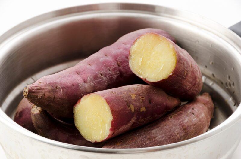 a closeup image of a steamer with sweet potatoes, one of which is cut in half