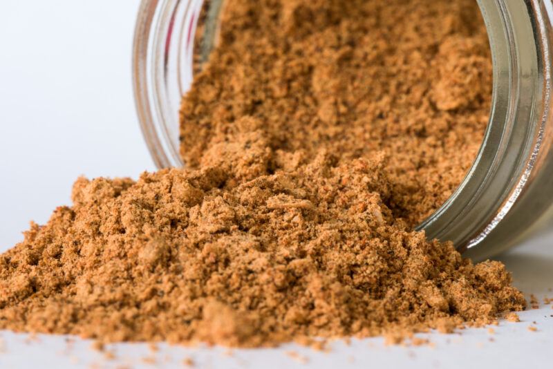 a closeup image of a jar toppled over with taco seasoning spilled from it