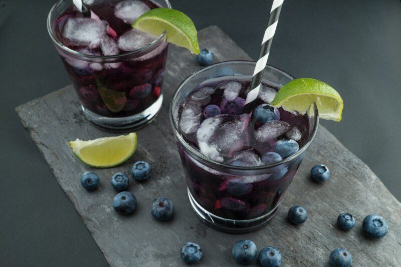 Two blueberry cocktails with lime wedges to represent the best blueberry vodka