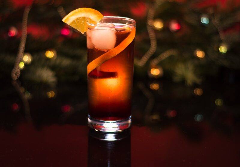 a glass of rum with a lemon wedge garnish and a blurred, colorful background to represent the best Cuban rum