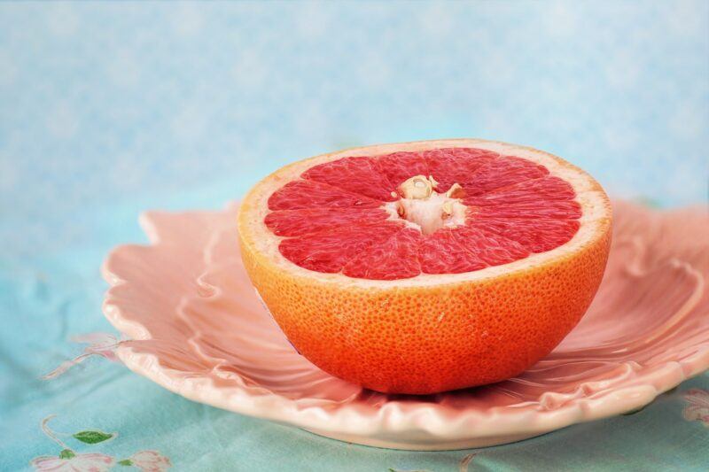 half a grapefruit sitting face up on a pretty pink dish to represent the best grapefruit vodka