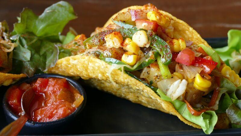 a close up of a stuffed taco and salsa dip on a plate to represent the best plant-based tacos