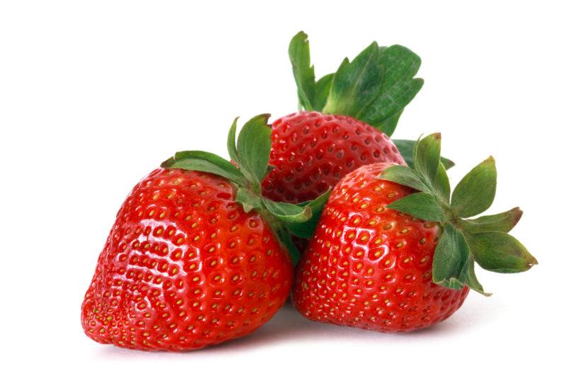 fresh strawberries with their stems still on, in a white background