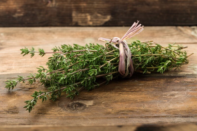 on a wooden surface is a bundle of fresh thyme