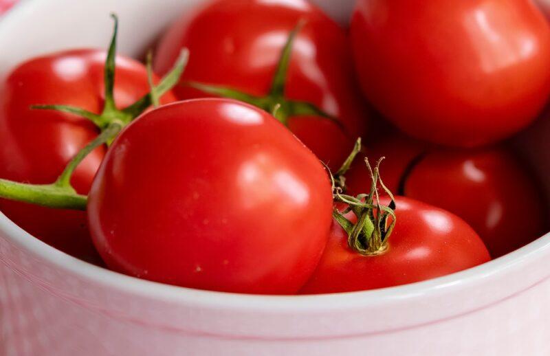 closeup image of a white bowl with fresh red tomatoes